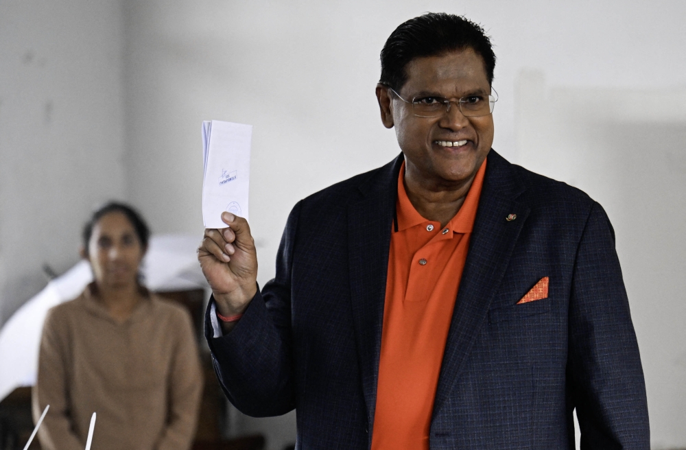 Suriname's President Chandrikapersad Santokhi shows his ballot at a polling station during parliamentary elections in Paramaribo on May 25, 2025. (Photo by Juan Barreto / AFP)
