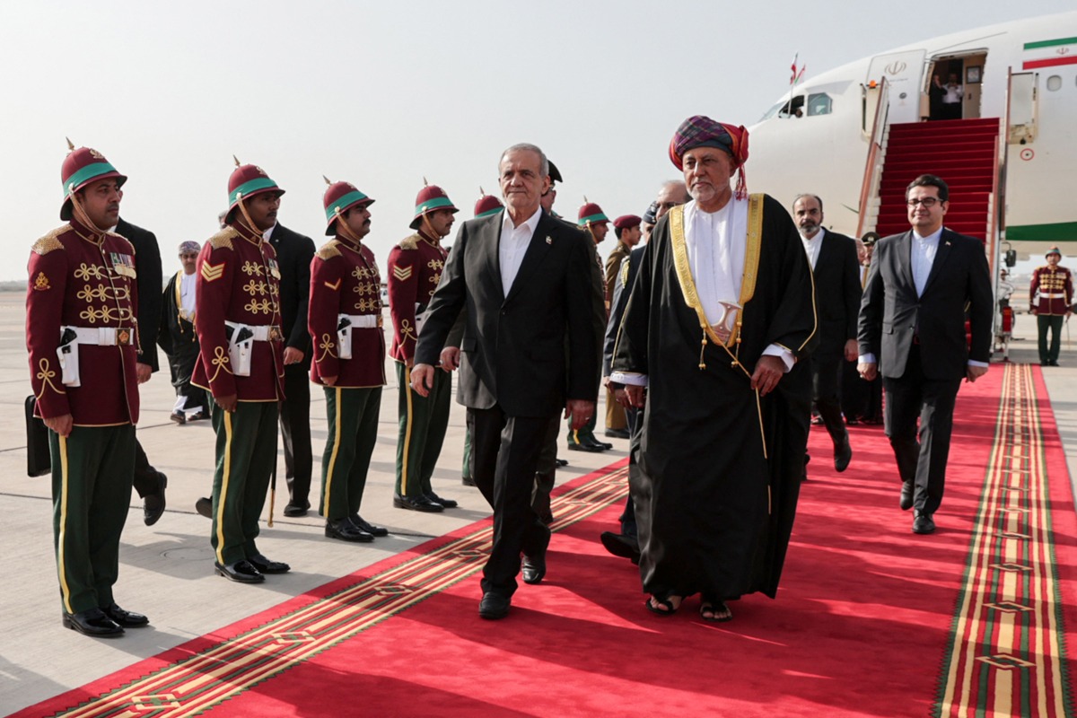 This handout picture provided by the Iranian presidential office shows Iran's President Masoud Pezeshkian (front C) being received by Oman's Sultan Haitham bin Tariq al-Said (front R) during a welcome ceremony at the airport in Muscat on May 27, 2025. (Photo by Iranian Presidency / AFP)