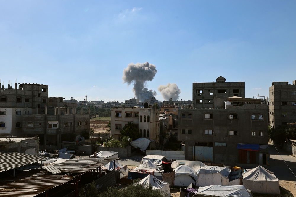 Smoke billows in the background during an Israeli strike, as pictured from the Nuseirat refugee camp in the central Gaza Strip, on May 29, 2025. (Photo by Eyad Baba / AFP)