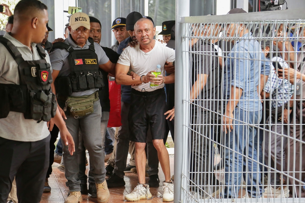 Filipino national Arnolfo Teves (centre), a murder suspect, is escorted by East Timorese security personnel for deportation to his home country at Nicolau Lobato airport in Dili on May 29, 2025. (Photo by Valentino Dariell De Sousa / AFP)