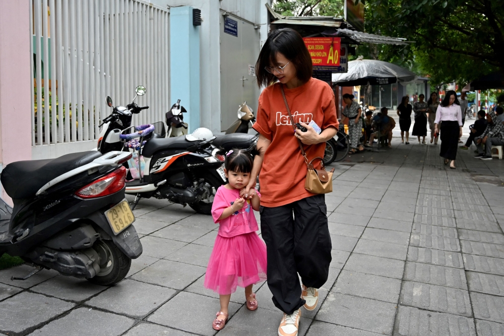 A mother takes her child to kindergarten in Hanoi on June 4, 2025. (Photo by Nhac Nguyen / AFP)