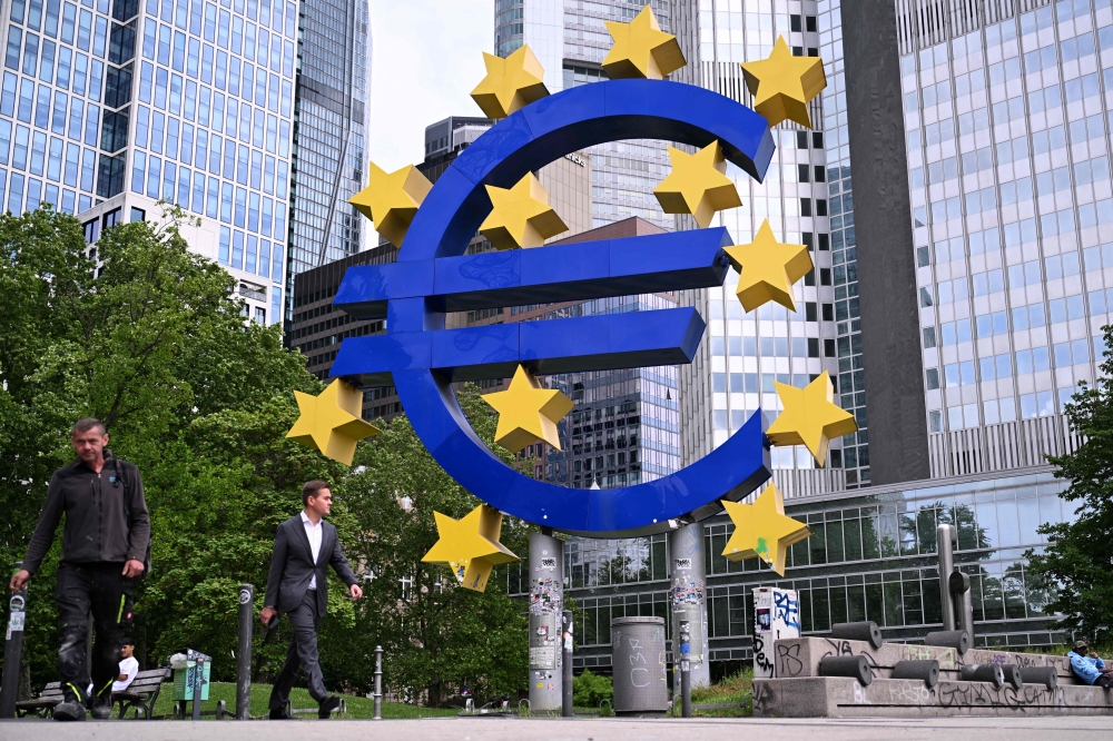 Pedestrians walk past the 'Euro Sculpture' by German artist Ottmar Hِrl in front of the former seat of the European Central Bank (ECB) at the Eurotower, ahead a press conference on the Eurozone's monetary policy, in Frankfurt am Main, western Germany, on June 5, 2025. (Photo by Kirill Kudryavtsev / AFP)

