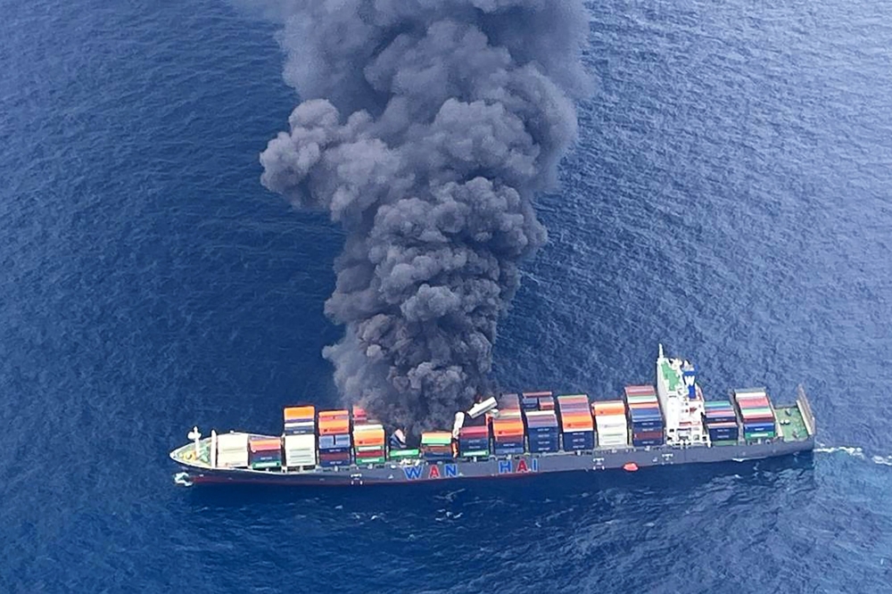 This handout photograph taken and released on June 9, 2025 by the Indian Coast Guard (ICG) shows smoke billowing from a cargo vessel that caught fire off Beypore coast in India's Kerala state. (Photo by Indian Coast Guard (ICG) / AFP) 