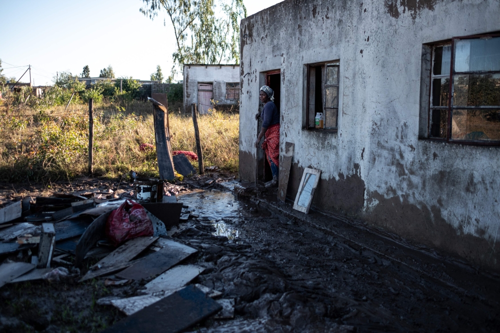 A resident of an informal settlement sweeps mud out of her dwelling after a flood near Mthatha on June 12, 2025. (Photo by Emmanuel Croset / AFP)
