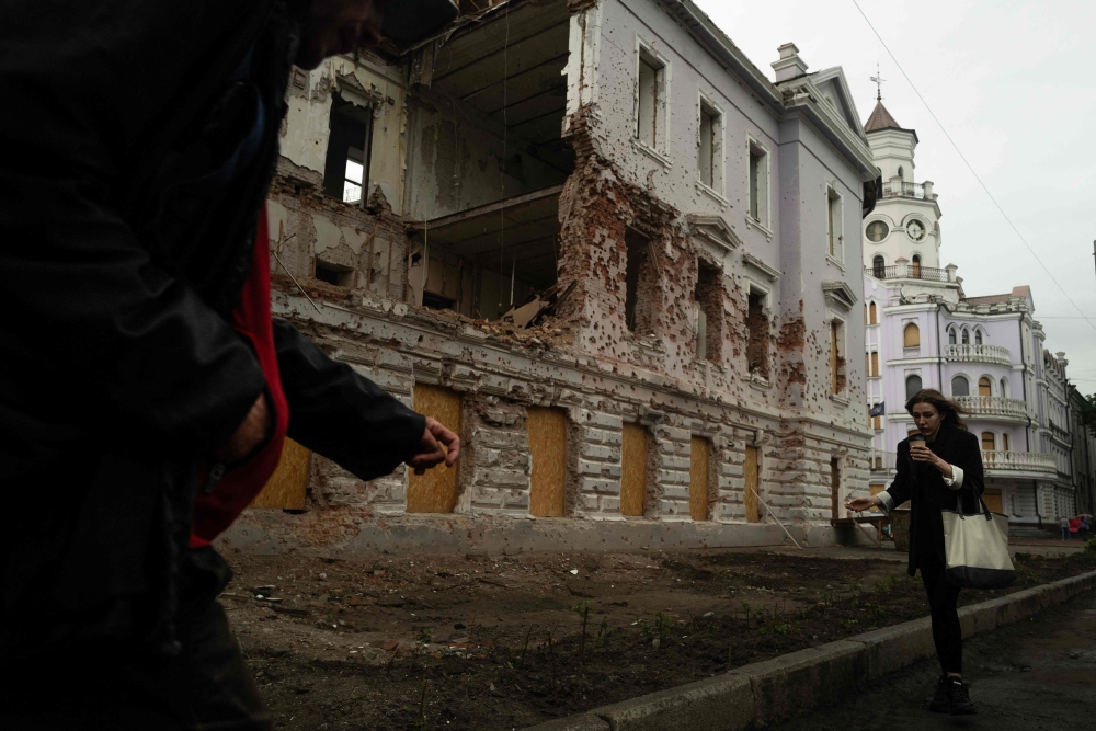 Pedestrians walk past a monument destroyed by Russian bombing in Sumy, north-eastern Ukraine, on June 12, 2025. (Photo by Florent Vergnes / AFP)
