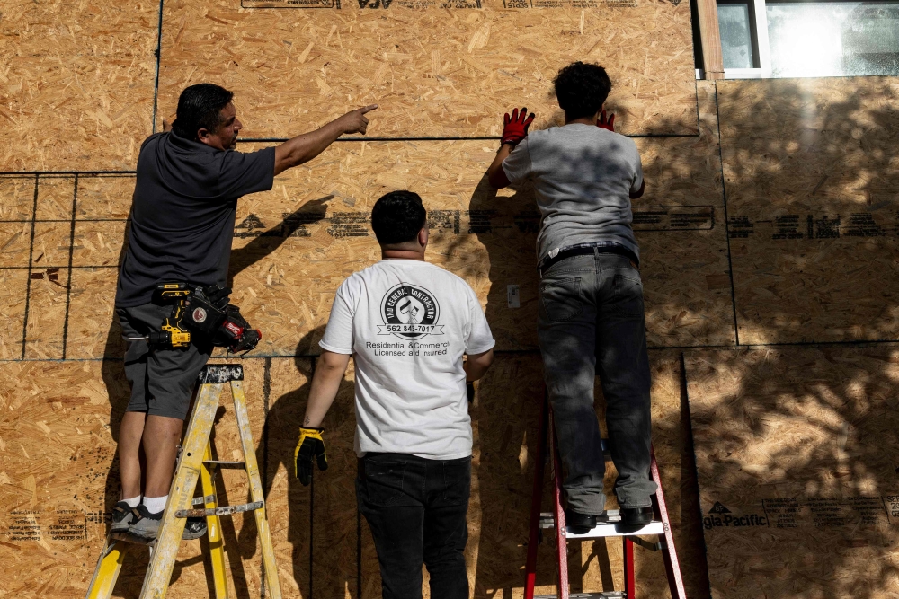 Workers board up a restaurant front in preparation for the No Kings protest in Los Angeles, on June 13, 2025. (Photo by Etienne Laurent / AFP)