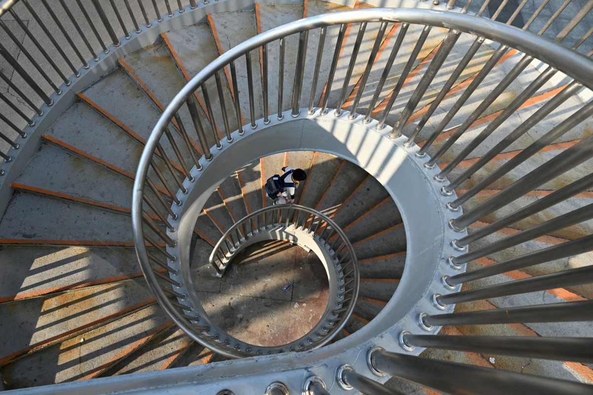A schoolboy walks up spiral stairs to a walkway in Beijing on June 17, 2025. (Photo by Adek BERRY / AFP)