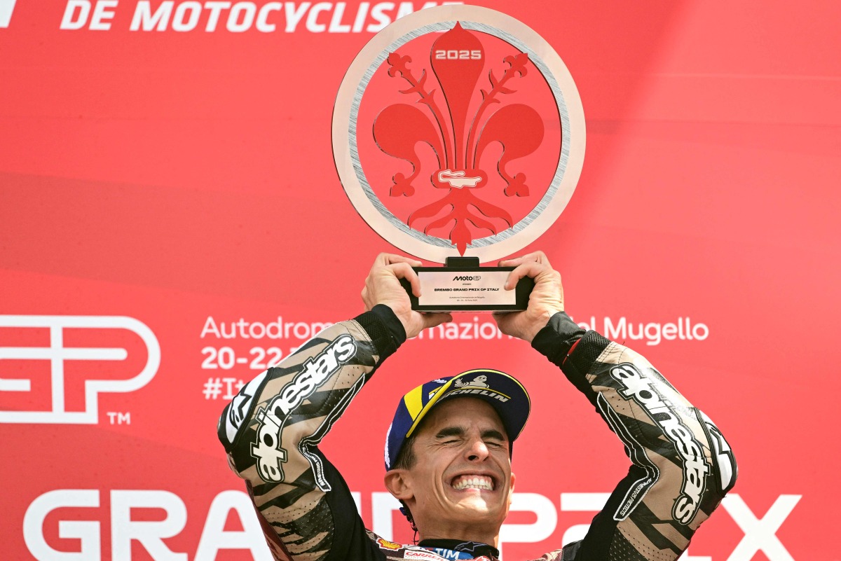 Winner Ducati Lenovoi Team's Spanish MotoGP rider Marc Marquez celebrates on the podium with the trophy after the Italian Moto GP Grand Prix at Mugello circuit, in Mugello, near Florence, on June 22, 2025. (Photo by Tiziana FABI / AFP)