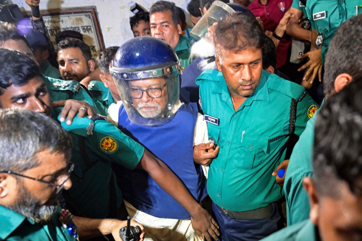 Police personnel escort KM Nurul Huda (C), Bangladesh's former Chief Election Commissioner to a court in Dhaka on June 23, 2025, a day after he was detained on charges of manipulating elections. (Photo by Munir UZ ZAMAN / AFP)