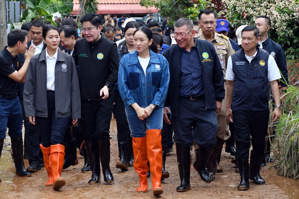 This handout photo from the Royal Thai Government taken and released on June 28, 2025 shows Thailand's Prime Minister Paetongtarn Shinawatra (C) visiting flood-damaged homes in Phaya Mengrai district in Thailand's northern province of Chiang Rai. (Photo by Handout / Royal Thai Government / AFP) 