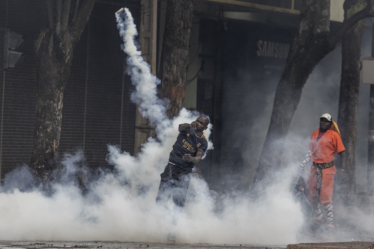 A protester hurls a teargas canister at Kenya police officers during clashes in downtown Nairobi on June 25, 2025 during a planned day of protest marking the first anniversary of the storming of the parliament. (Photo by SIMON MAINA / AFP)
