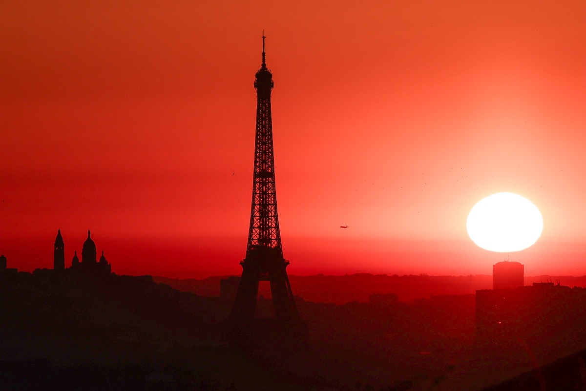 Photo used for representational purposes. The sun rises by the Eiffel Tower and the Sacre Coeur Basilica ontop of the Montmartre hill in Paris on July 1, 2025, as the city is on red alert for high temperatures, with the top of the Eiffel Tower shut, polluting traffic banned and speed restrictions in place as a searing heatwave gripped Europe. Photo by Thibaud MORITZ / AFP.