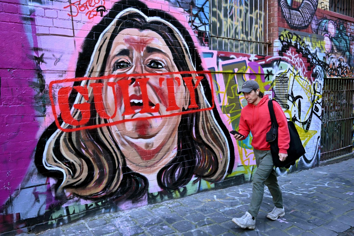 A man walks past a mural by street artist Jarrod Grech of Erin Patterson - now stamped with a guilty sign - of the Australian woman found guilty of murdering three members of her husband's family with a toxic mushroom-laced beef Wellington lunch, in Melbourne on July 9, 2025. Photo by William WEST / AFP