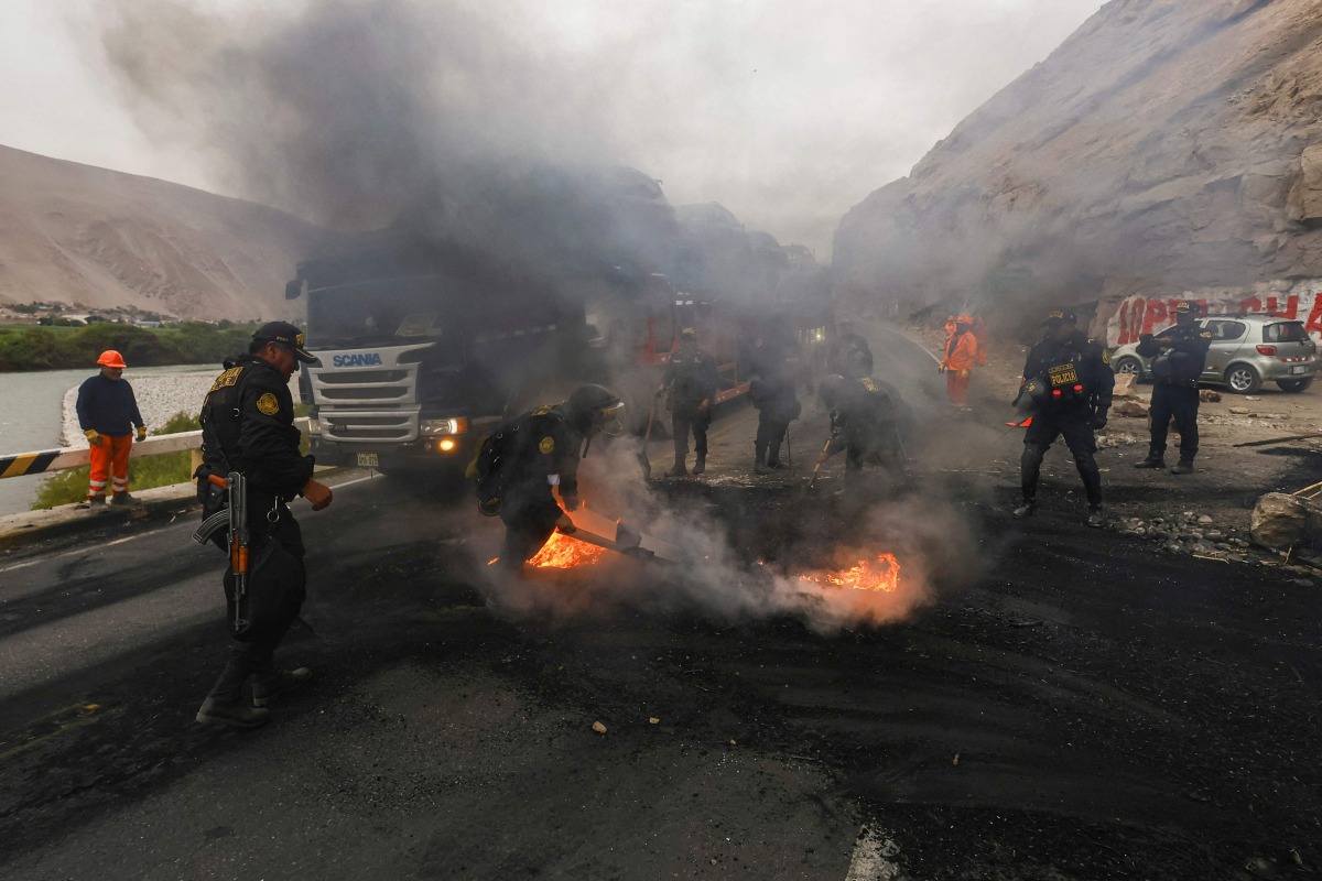 Police officers clear a road that was blocked by miners during a protest at kilometer 782 of the Pan-American Highway South, near the Ocona Bridge, in the province of Camana, Arequipa Department, southern Peru, on July 11, 2025. Road unblocking operations in southern Peru left one dead and 20 injured on Friday, including seven officers, amid protests by informal miners who reject government demands to legalize their activity, authorities reported. (Photo by Juan Jose SANTY / AFP)
