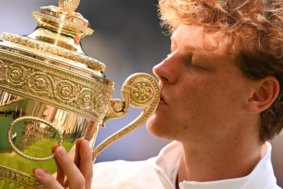 Italy's Jannik Sinner kisses the winner's trophy as he poses for pictures following his victory against Spain's Carlos Alcaraz at the end of their men's singles final tennis match on the fourteenth day of the 2025 Wimbledon Championships at The All England Lawn Tennis and Croquet Club in Wimbledon, southwest London, on July 13, 2025. (Photo by Kirill KUDRYAVTSEV / AFP)