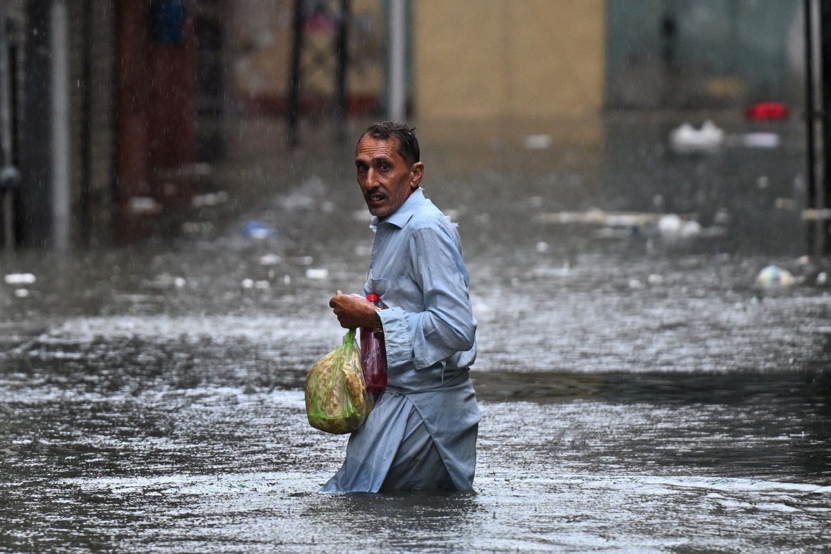 A man wades through a flooded street during heavy monsoon rains in Rawalpindi on July 17, 2025. Photo by Aamir QURESHI / AFP