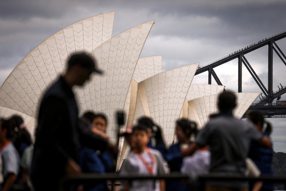 Tourists pose for photographs in front of the Sydney Opera House and Sydney Harbour Bridge on March 31, 2025. Photo by DAVID GRAY / AFP
