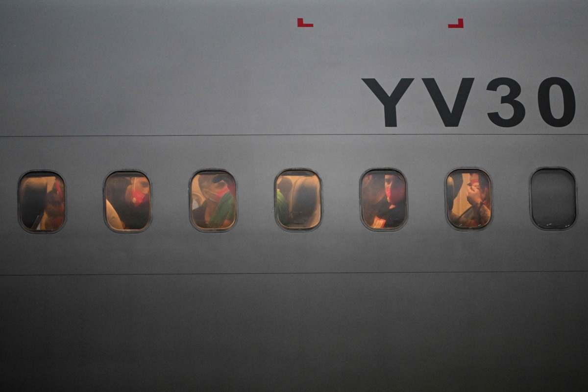 Venezuelan migrants who were jailed in El Salvador look out the windows of the plane as it lands at Simon Bolivar International Airport in Maiquetia, Venezuela on July 18, 2025. (Photo by Federico PARRA / AFP)