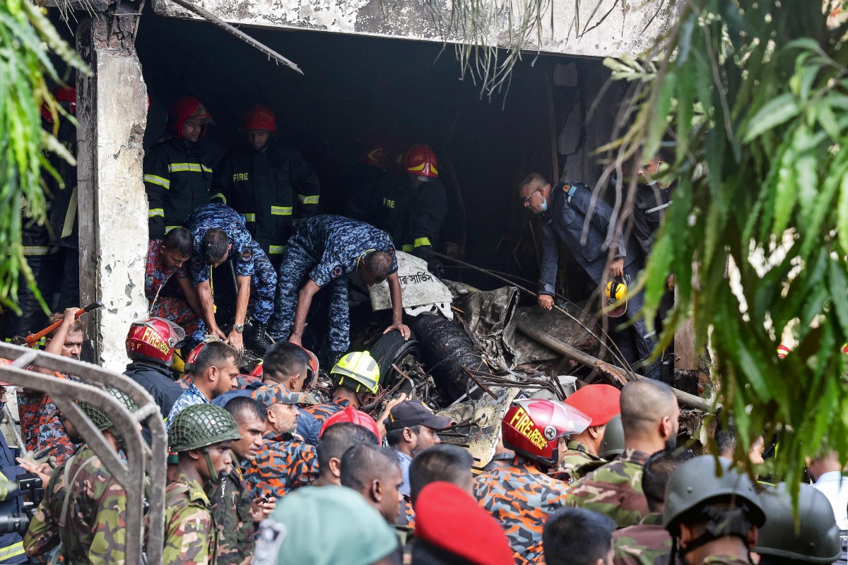 Bangladesh's fire service and security personnel conduct a search and rescue operation after a Air Force training jet crashed into school in Dhaka on July 21, 2025. (Photo by Abdul Goni / AFP)
 