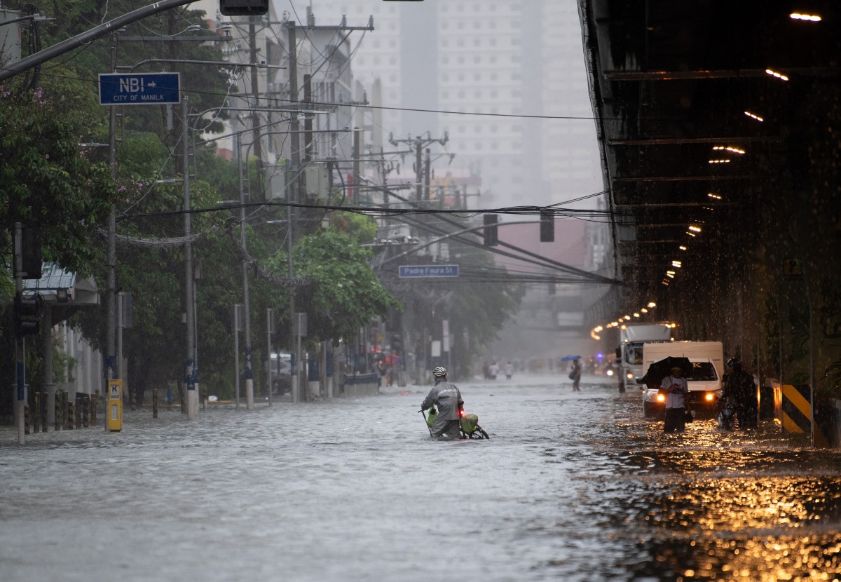 A cyclist crosses a flooded street in Manila on July 22, 2025, after heavy rains caused floodings enhanced by monsoon. Photo by Ted ALJIBE / AFP