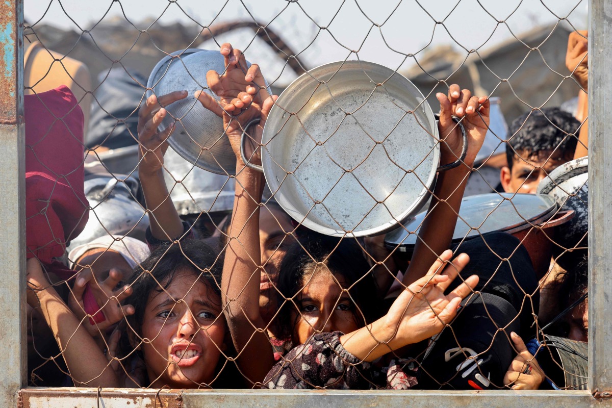 Palestinians, mostly children, push to receive a hot meal at a charity kitchen in the Mawasi area of Khan Yunis in the southern Gaza Strip on July 22, 2025. (Photo by AFP)
