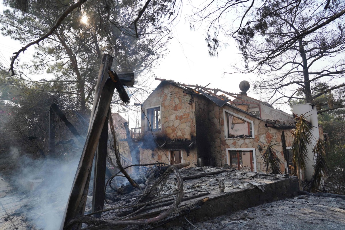 Smoke rises from the embers of a burnt house as firefighters battle a forest fire in the Cypriot village of Souni, in the Limassol province, on July 24, 2025. (Photo by Etienne TORBEY / AFP)