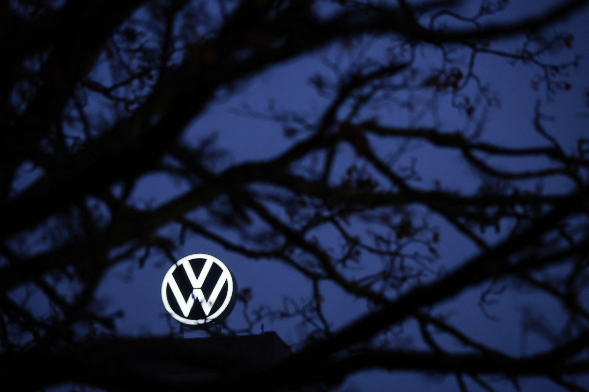 The logo of German carmaker Volkswagen (VW) is seen behind a tree at the company's headquarters in Wolfsburg, central Germany, on December 4, 2024. Photo by Ronny HARTMANN / AFP