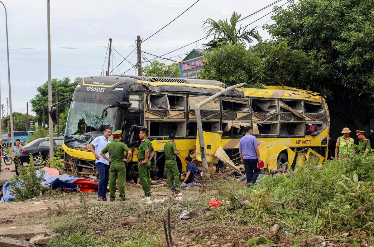 This handout photograph taken and released by the Vietnam News Agency (VNA) on July 25, 2025 shows security personnel along with authorities standing next to a crashed bus in Ha Tinh province, Central Vietnam. (Photo by Vietnam News Agency / AFP)