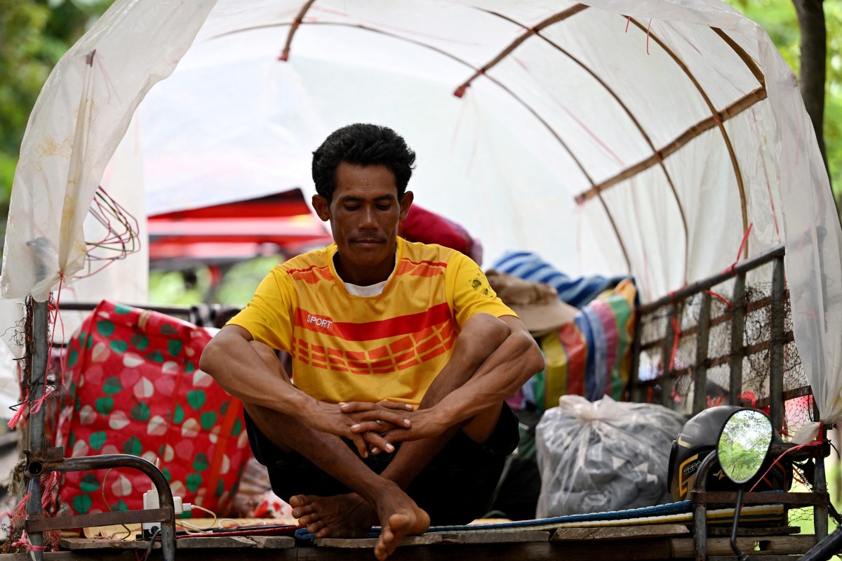 A villager who fled his home near the Cambodia-Thailand border sits on a cart on the grounds of a pagoda in Oddar Meanchey province on July 25, 2025. Photo by TANG CHHIN Sothy / AFP.