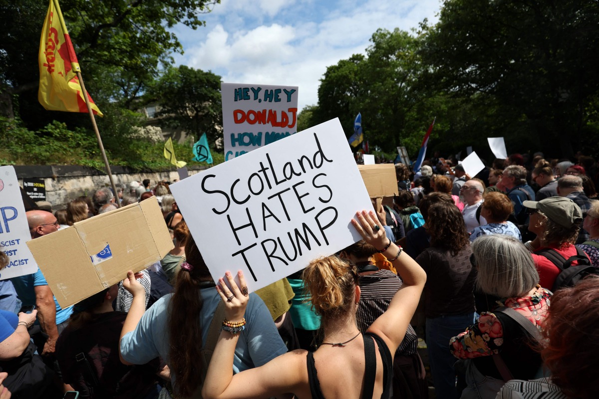 Demonstrators hold placards during a 'Stop Trump Coalition' protest near the US Consulate building in Edinburgh, Scotland on July 26, 2025. (Photo by SCOTT HEPPELL / AFP)
