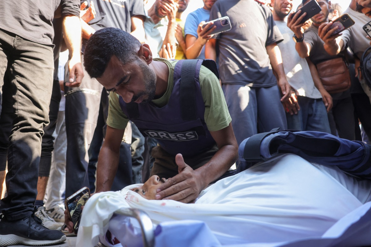 A colleague mourns Palestinian journalist Adam Abu Harbid, killed in overnight Israeli strikes, during his funeral at the Al-Shifa hospital in Gaza City on July 25, 2025. Photo by BASHAR TALEB / AFP.
