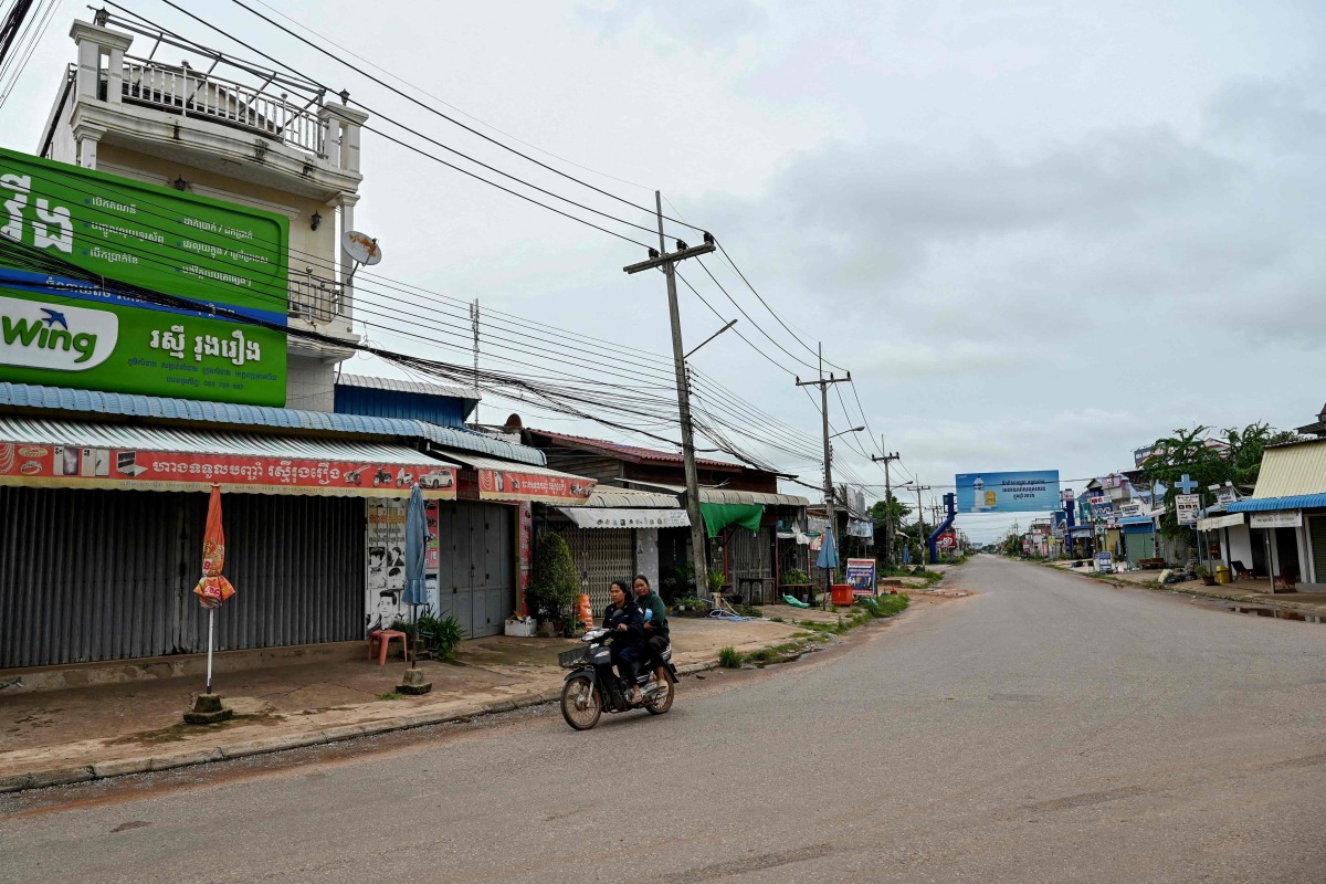 Women ride along a quiet street in Samraong, some 20 kilometres from the border conflict zone, in Cambodia's Oddar Meanchey province on July 27. (Photo by TANG CHHIN Sothy / AFP)