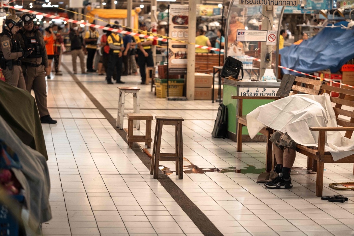 The body of a suspected shooter is covered with a sheet on a bench at Or Tor Kor Market in Bangkok on July 28, 2025. Photo by Chanakarn Laosarakham / AFP