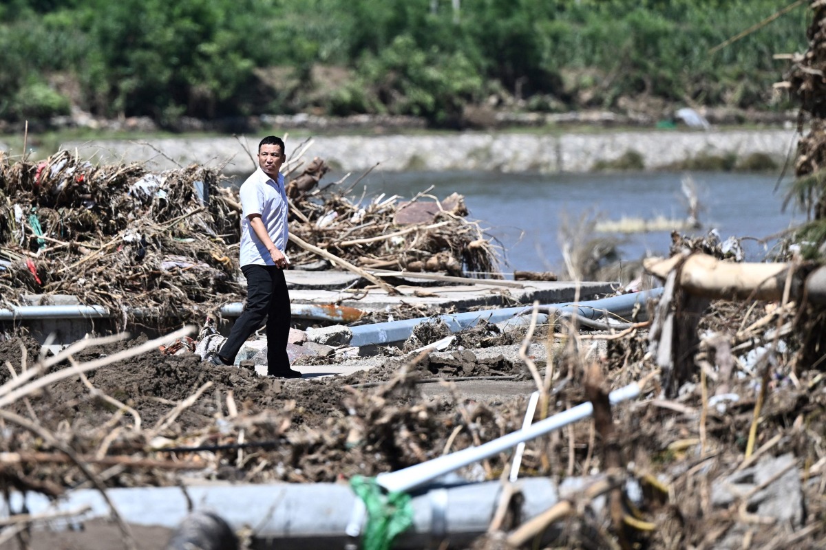 A man walks past a rain damaged area from the past few days in Huairou district, on the outskirts of Beijing on July 30, 2025. Photo by Pedro Pardo / AFP