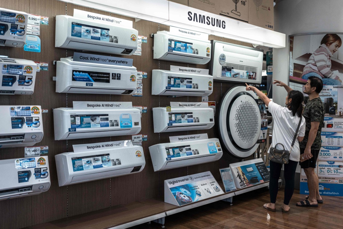 People looks at Samsung air conditioners displayed for sale at a home improvement store in Bangkok on August 1, 2025. (Photo by Chanakarn Laosarakham / AFP)
