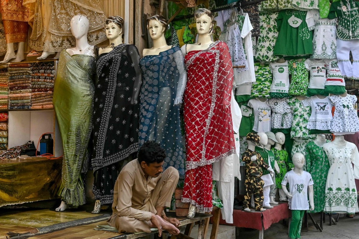 A clothing vendor waits for customers at a market in Lahore on July 31, 2025. (Photo by Arif ALI / AFP)
