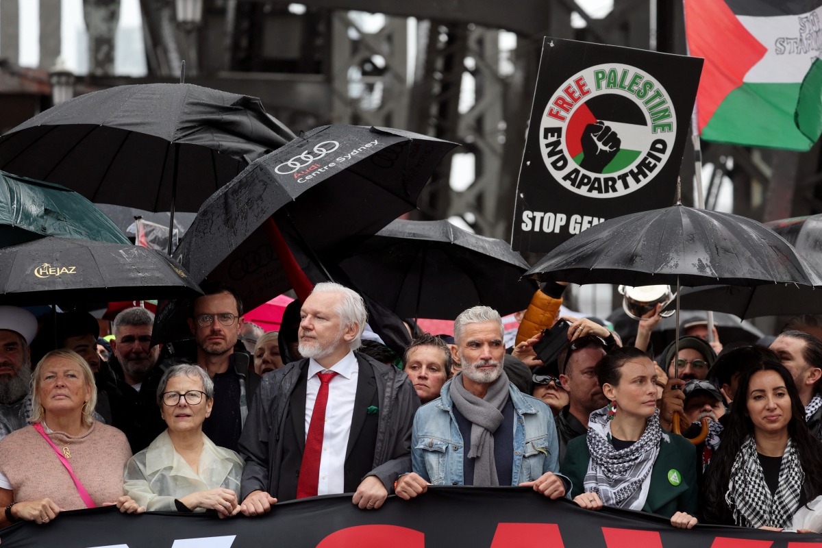 Demonstrators including WikiLeaks founder Julian Assange (3rd L, wearing red tie) cross the Sydney Harbour Bridge during a pro-Palestinian rally against Israel's actions and the ongoing food shortages in the Gaza Strip, in Sydney on August 3, 2025. (Photo by DAVID GRAY / AFP)
