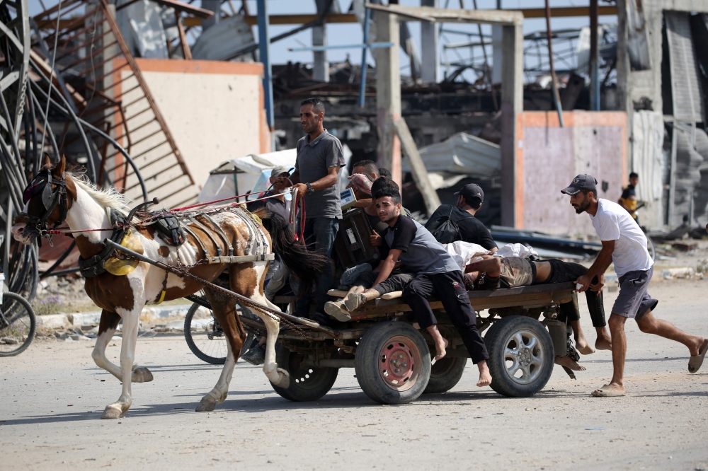 Palestinians transport men either killed or wounded while seeking food at an aid distribution point on Salah al-Din road near the Nusseirat refugee camp in the central Gaza Strip on August 2, 2025. (Photo by Eyad Baba / AFP)