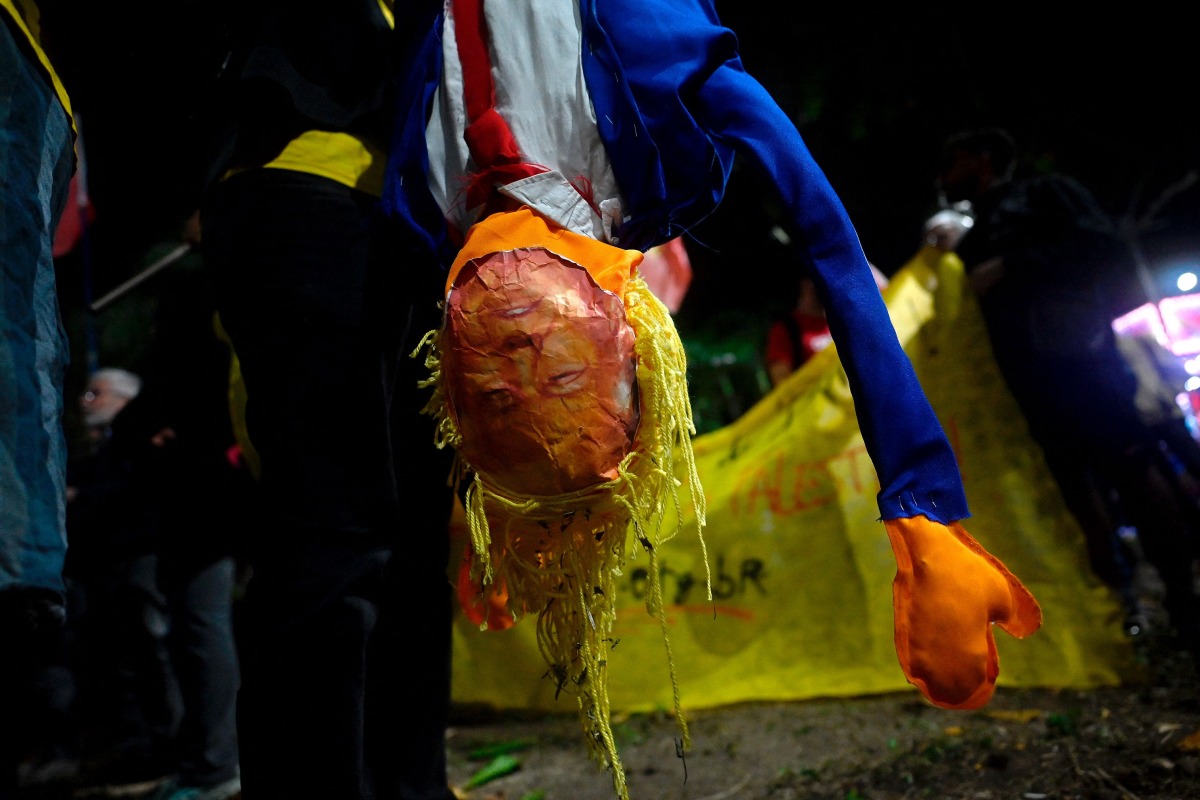 A person holds a dummy depicting US President Donald Trump during a protest in defense of national sovereignty after trade tariffs and sanctions were imposed by the US government on Brazil, near the US consulate in Rio de Janeiro, Brazil on August 1, 2025. (Photo by Mauro PIMENTEL / AFP)
