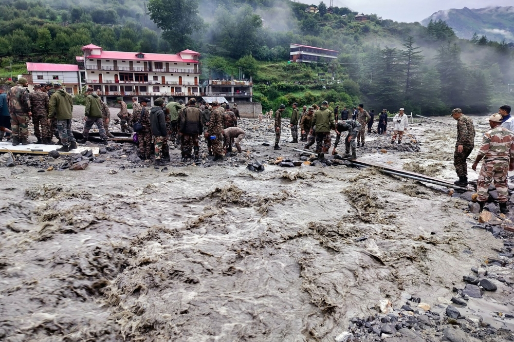 This handout photograph released on August 6, 2025 by the Indian Army shows security and relief personnel heaving rocks and removing debris to build a crossing across a stream of dense sludge during a search and rescue operation, a day after a cloudburst caused a massive mudslide and flash floods in India's Uttarakhand state.  (Photo by Indian Army / AFP) 