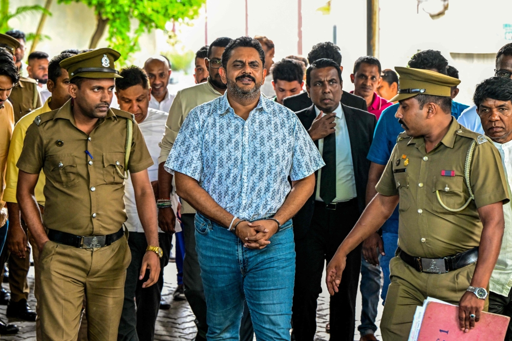 Police escort Sri Lanka's former Agriculture Minister Shasheendra Rajapaksa (centre) to a prison in Colombo on August 6, 2025. (Photo by Ishara S. Kodikara / AFP)

