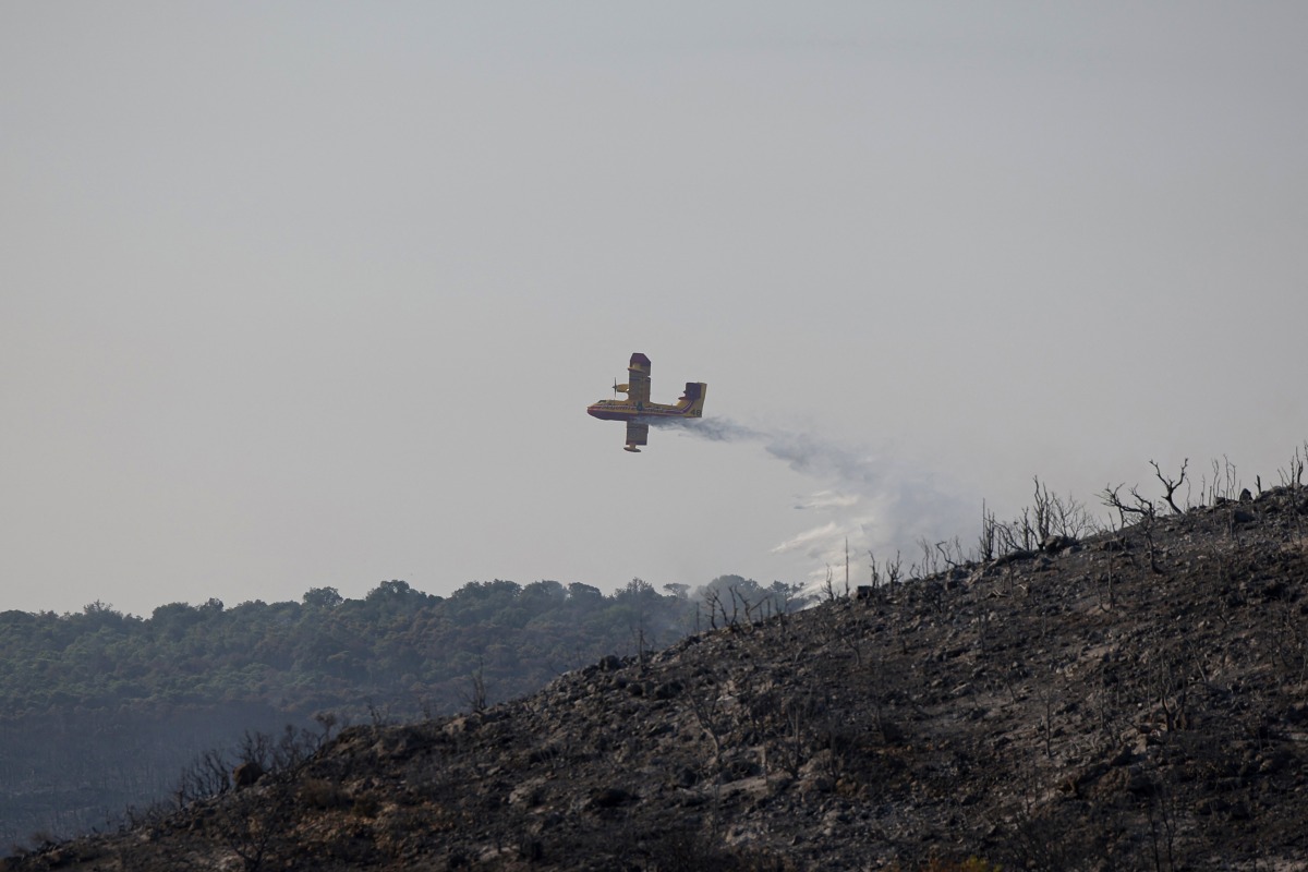 A Canadair aircraft of the French civil security drops fire retardant over a wildfire in Villeseque-Corbieres, southern France on August 7, 2025. Photo by Valentine CHAPUIS / AFP.
