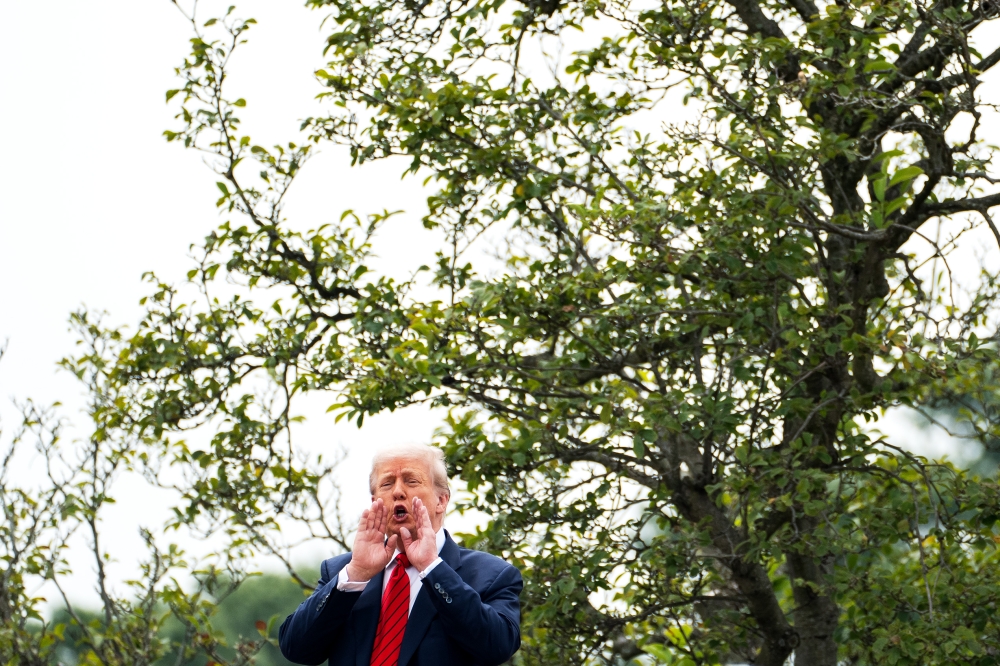 President Donald Trump shouts to reporters from the roof of the White House. (Photo by Demetrius Freeman/The Washington Post)