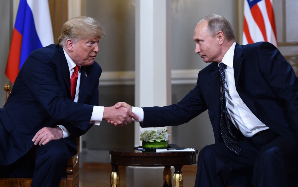 File: Russian President Vladimir Putin (right) and US President Donald Trump shake hands before a meeting in Helsinki on July 16, 2018. (Photo by Brendan Smialowski / AFP)
