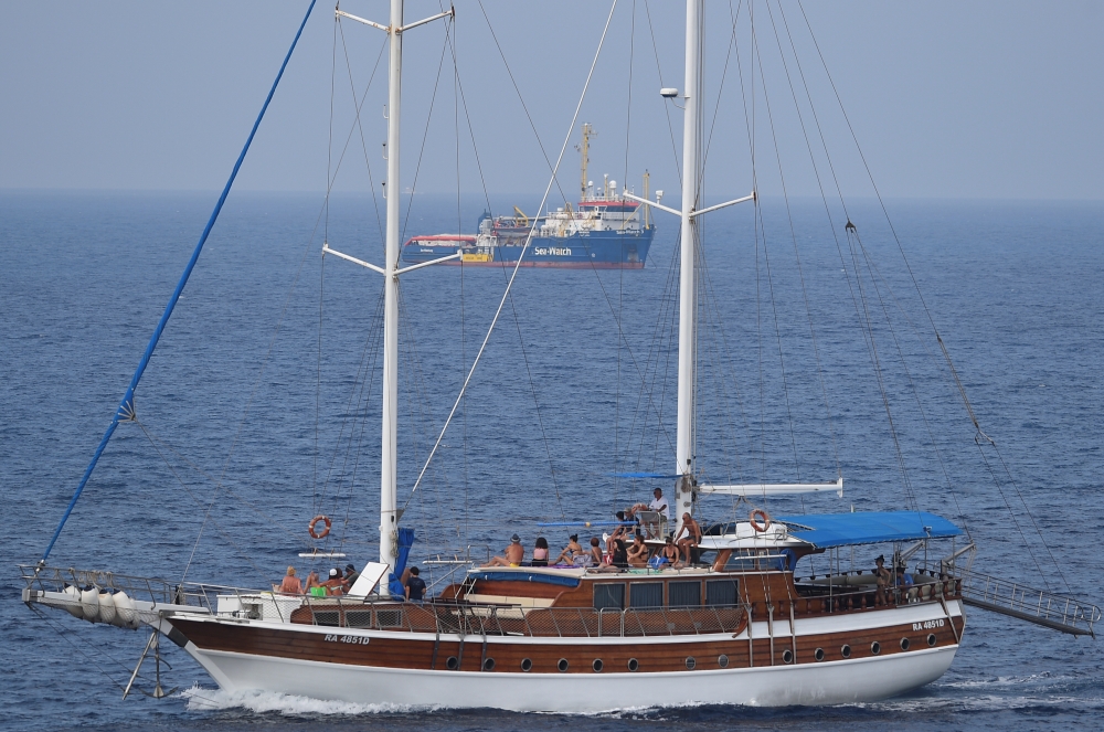 File photo: A tourist boat passes by search and rescue ship Sea-Watch 3 as it remains blocked near the island of Lampedusa, Italy, June 28, 2019. Reuters/Guglielmo Mangiapane