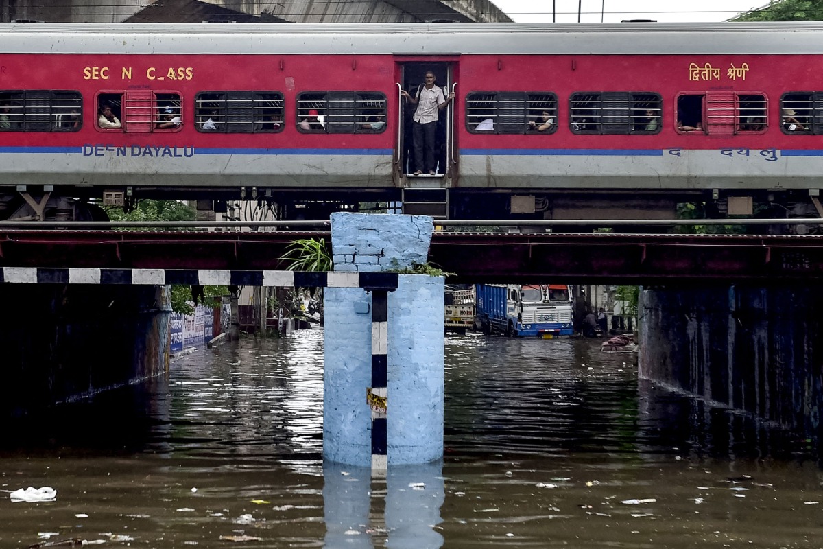 A train crosses over a flooded railway bridge during heavy rainfall in Jalandhar on August 14, 2025. (Photo by Shammi MEHRA / AFP)
