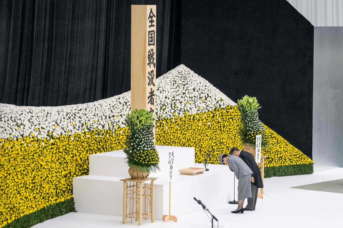 Japan's Emperor Naruhito (R) and Empress Masako bow as they attend a memorial service marking the 80th anniversary of Japan's surrender in World War II at the Nippon Budokan hall in Tokyo on August 15, 2025. (Photo by Yuichi YAMAZAKI / AFP)