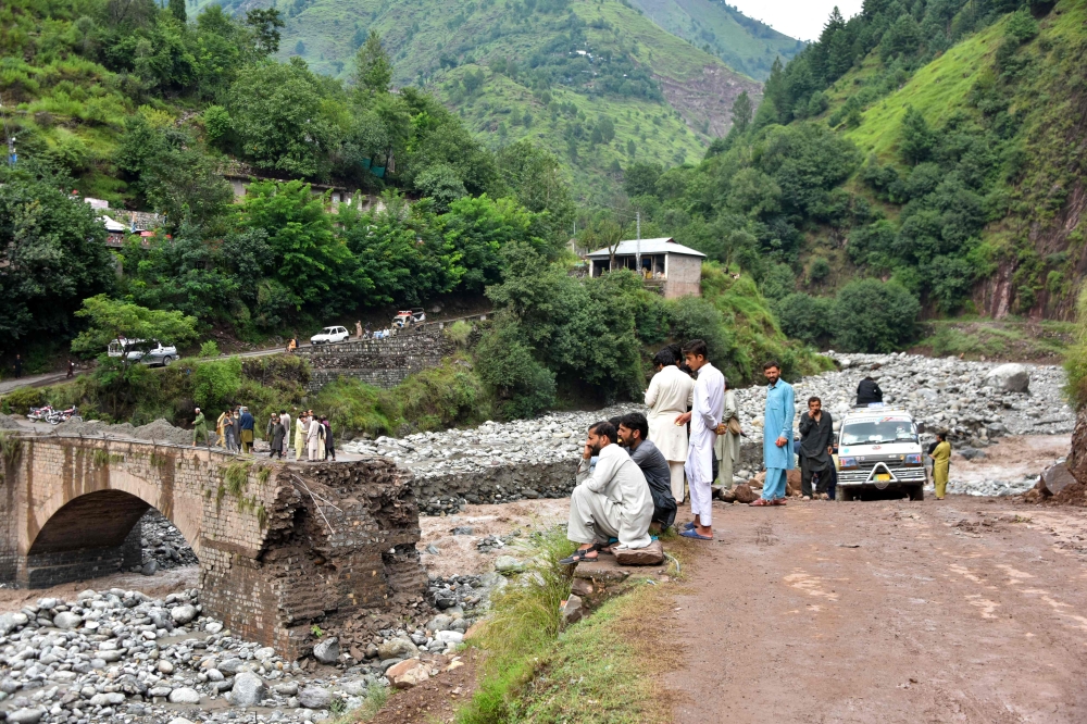 Onlookers gather near a destroyed bridge after flash floods on the outskirts of Muzaffarabad, the capital of Pakistan-administered Kashmir, on August 15, 2025. (Photo by Sajjad Qayyum / AFP)