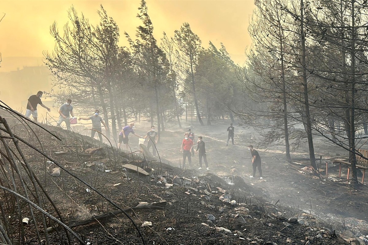 This handout photograph taken and released on August 8, 2025 by Turkish news agency DHA (Demiroren News Agency) shows people working to extinguish wildfire in Canakkale, northwestern Turkey in the Marmara region. (Photo by Handout / DHA (Demiroren News Agency) / AFP)