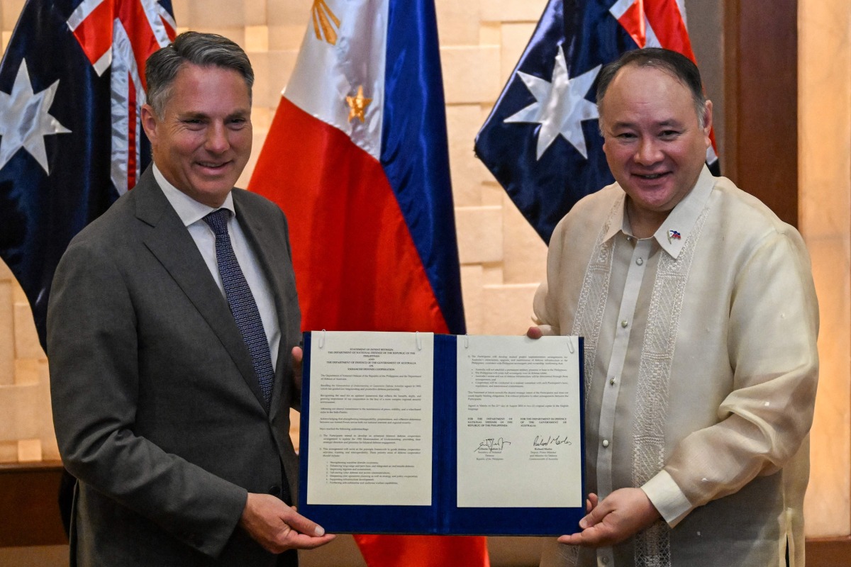 Philippine Defence Minister Gilberto Teodoro (R) and Australian Deputy Prime Minister and Minister for Defence Richard Marles (L) pose for a photo after signing the statement of intent for the enhanced defence cooperation in Makati, Metro Manila on August 22, 2025. (Photo by Jam STA ROSA / AFP)
